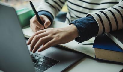 Main d'une personne devant un PC avec un livre